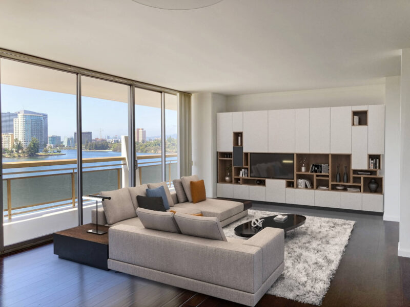 Liviing room of an apartment at 1200 Lakeshore with a view of Oakland across the lake through the floor to ceiling windows behind the room.